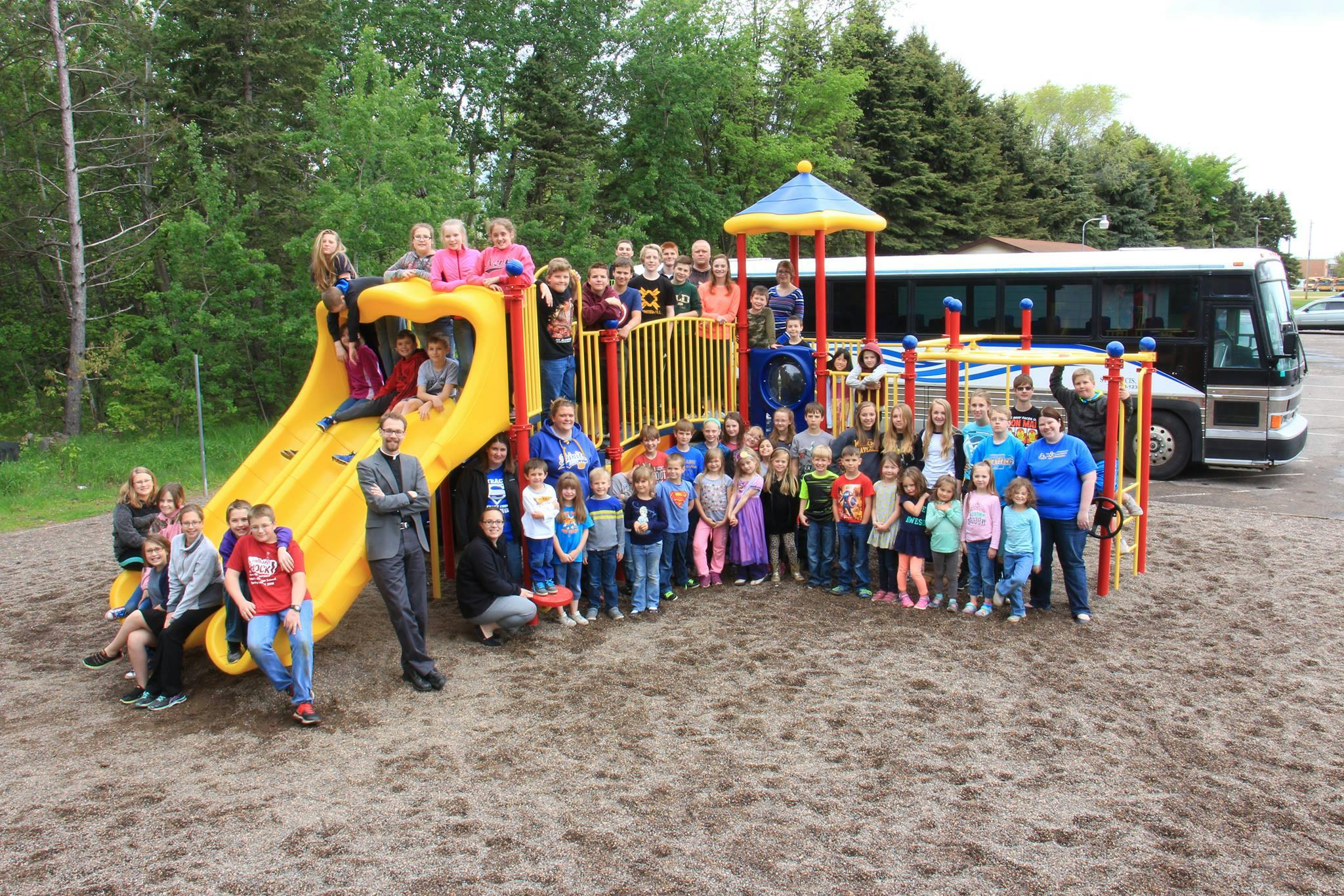 Group of children and adults posing on and around a playground structure