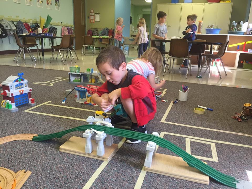 Child playing with a toy train set on the floor