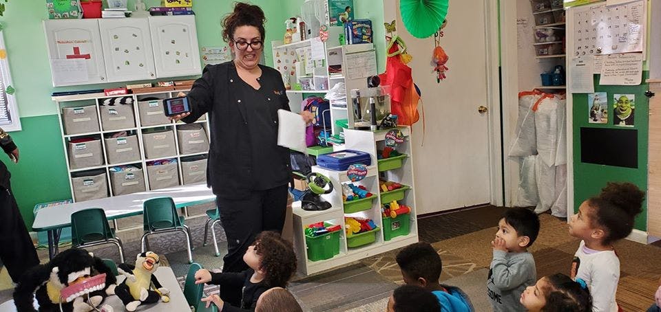 Person in scrubs teaching children in a classroom