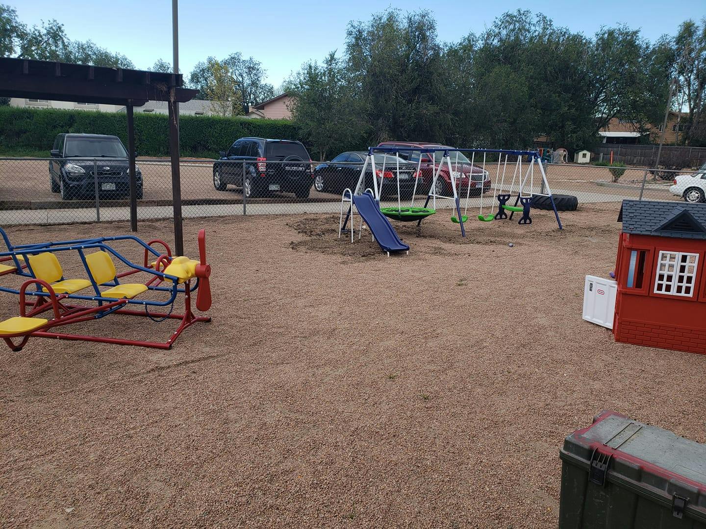Playground with swings, slide, and a red playhouse