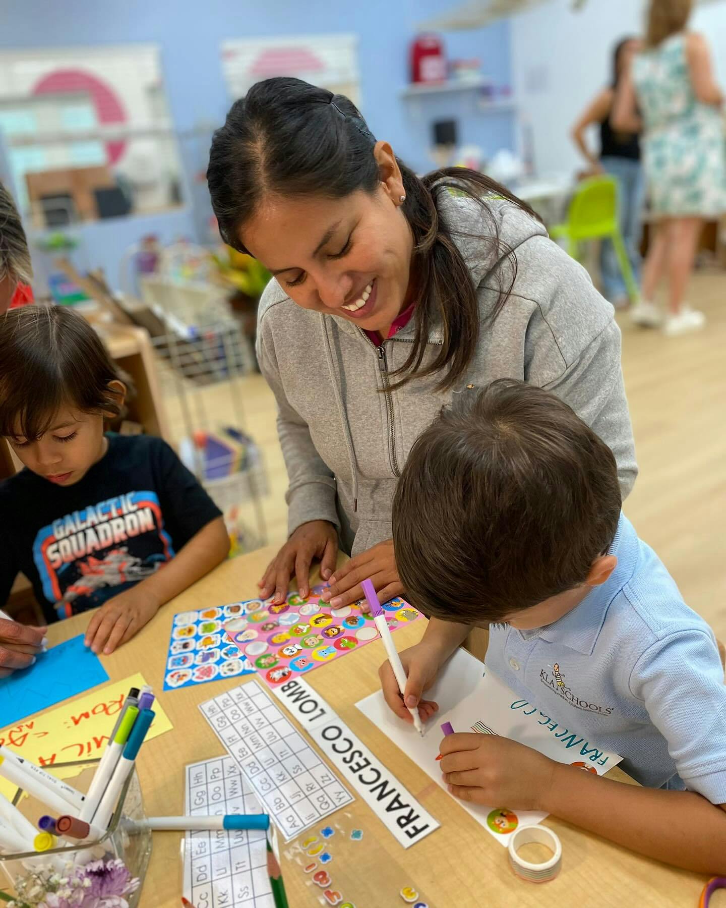 Adult and two children drawing and working with stickers at a table