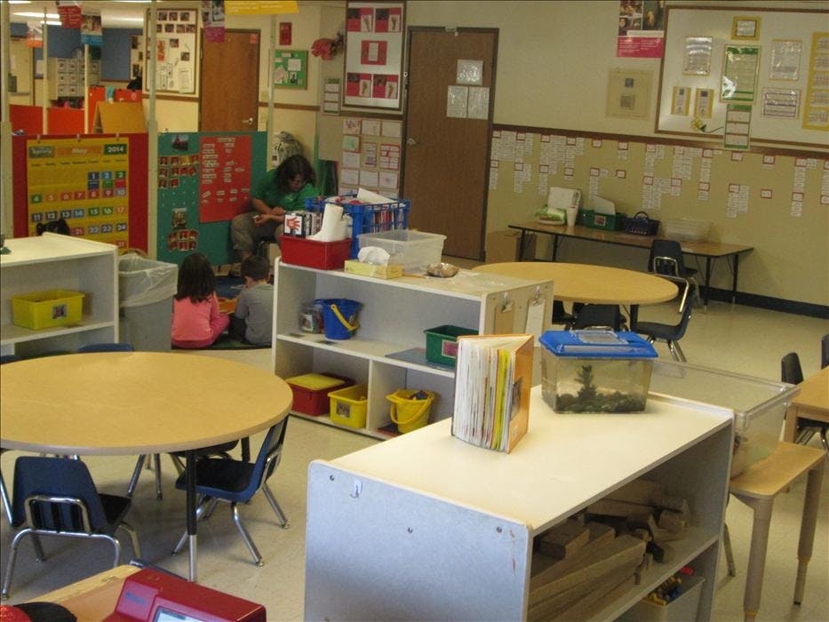 Adult and two children on the floor in a classroom