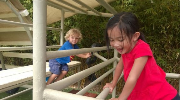Child in red shirt and child in blue shirt on playground equipment