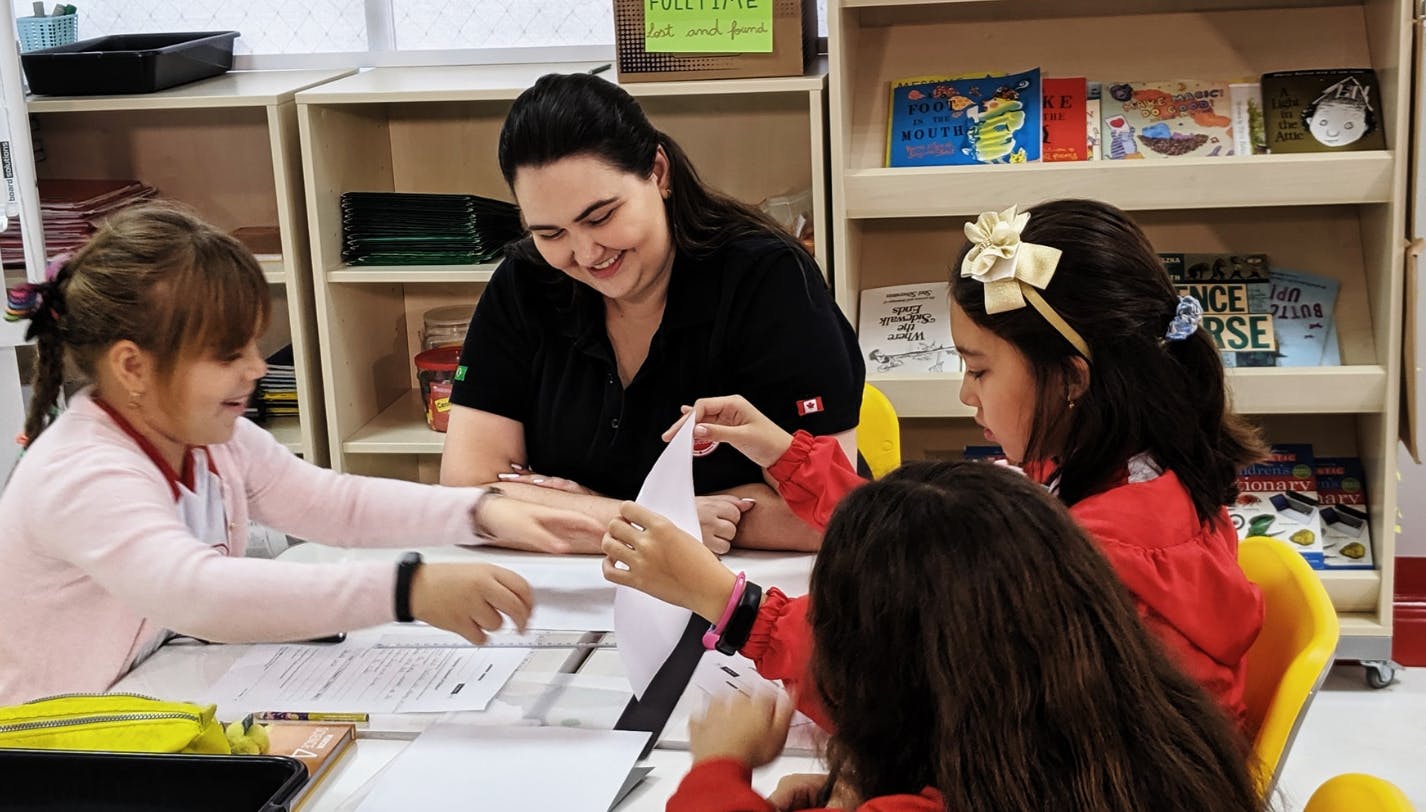 Adult and three children at a table in a classroom