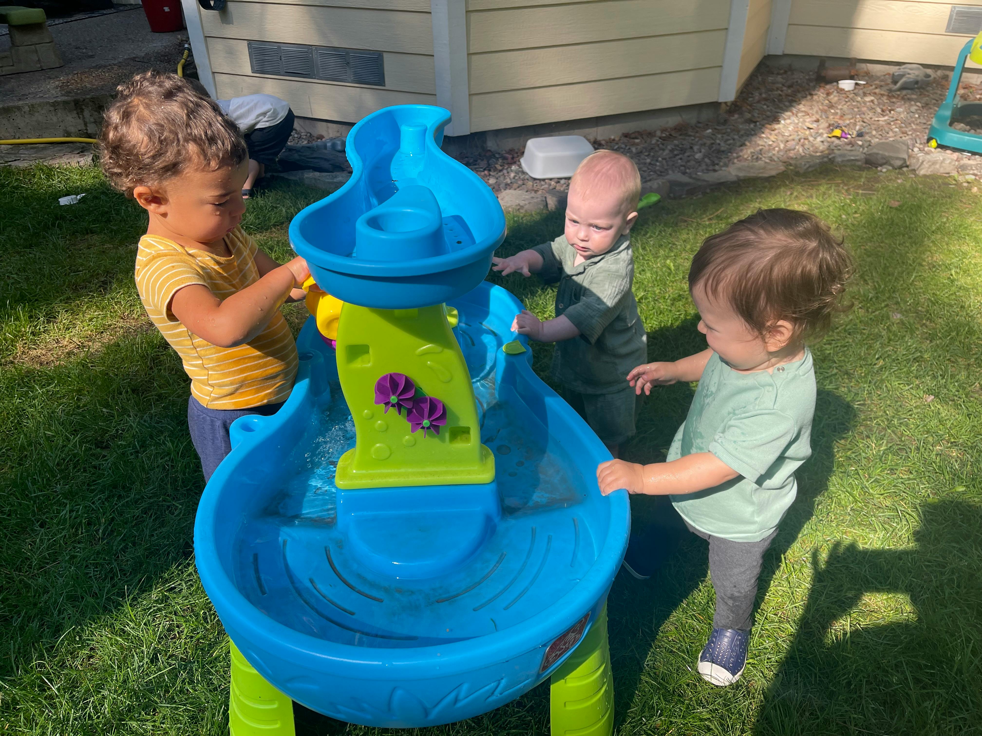 Three children playing with a water table outdoors