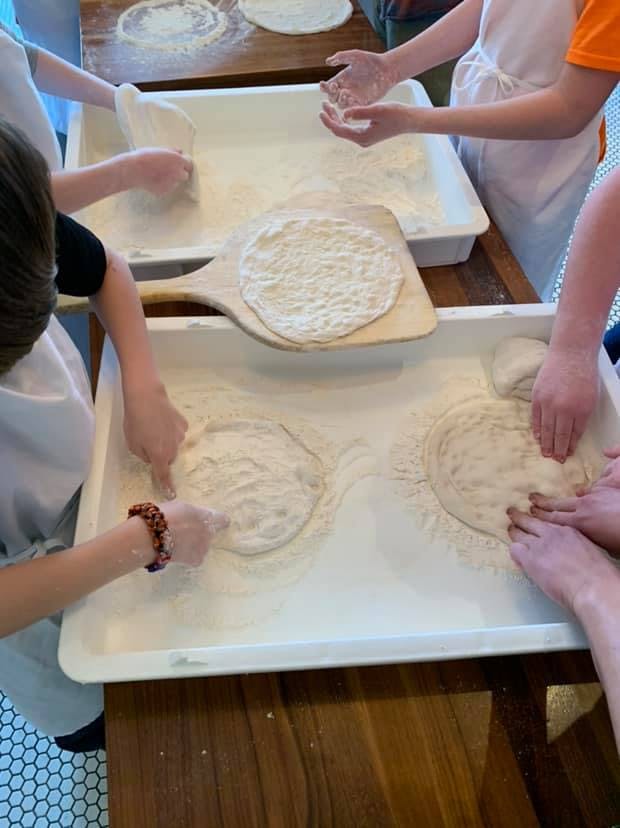 People making pizza dough in a kitchen