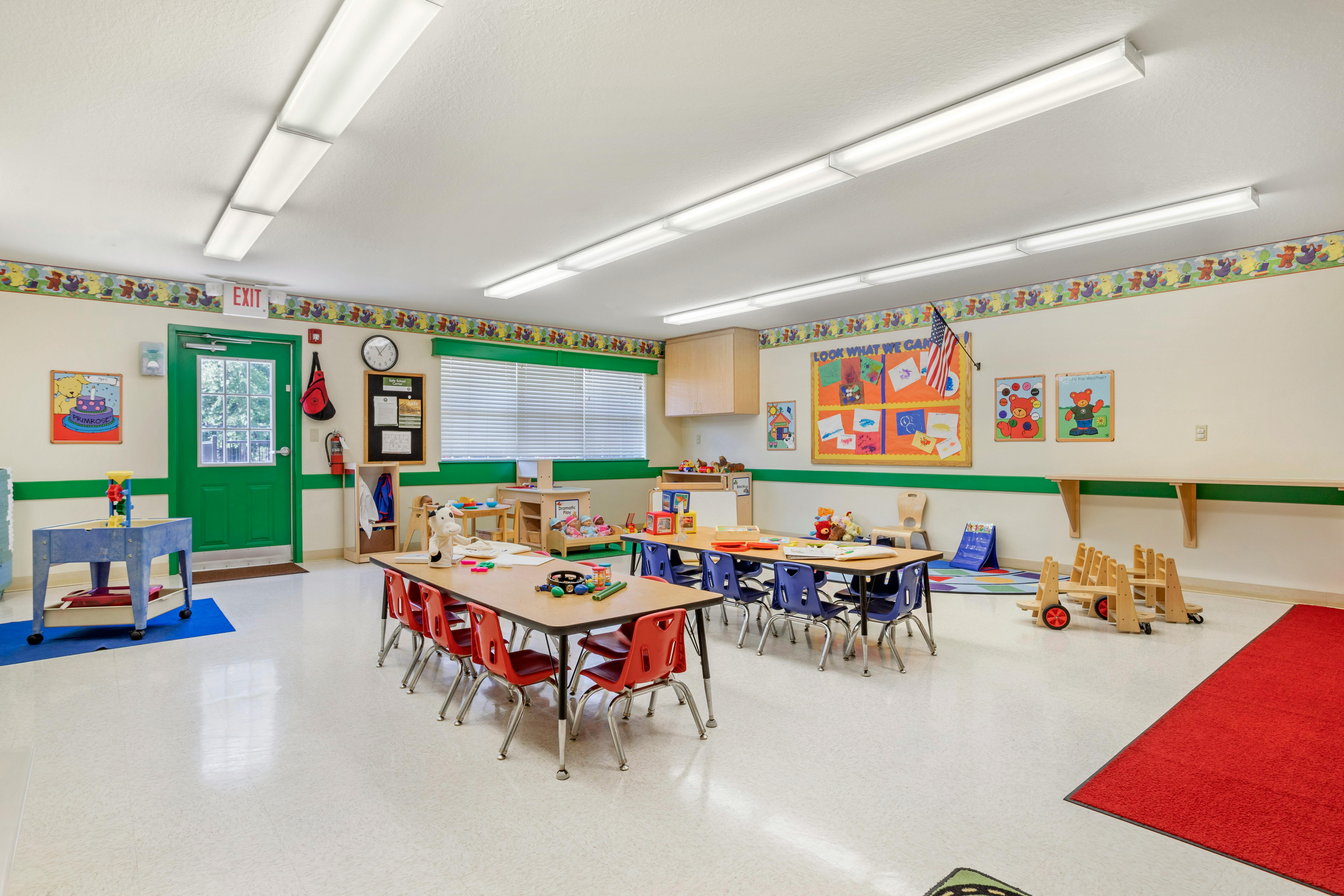 Classroom with small tables and chairs, shelves, and educational posters