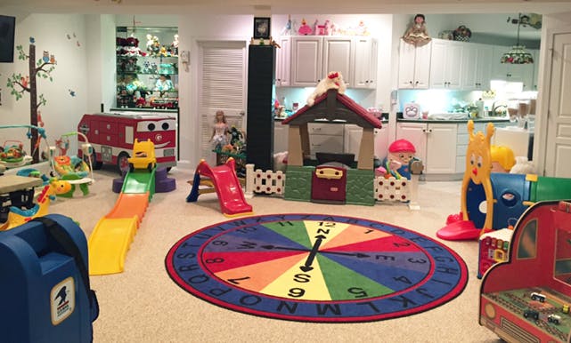 Indoor play area with slides, playhouses, and a colorful clock rug