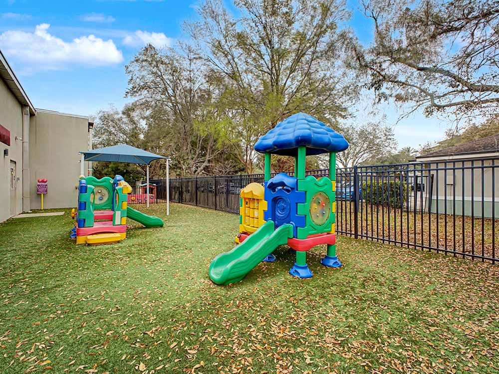 Colorful playground equipment on artificial turf with scattered leaves