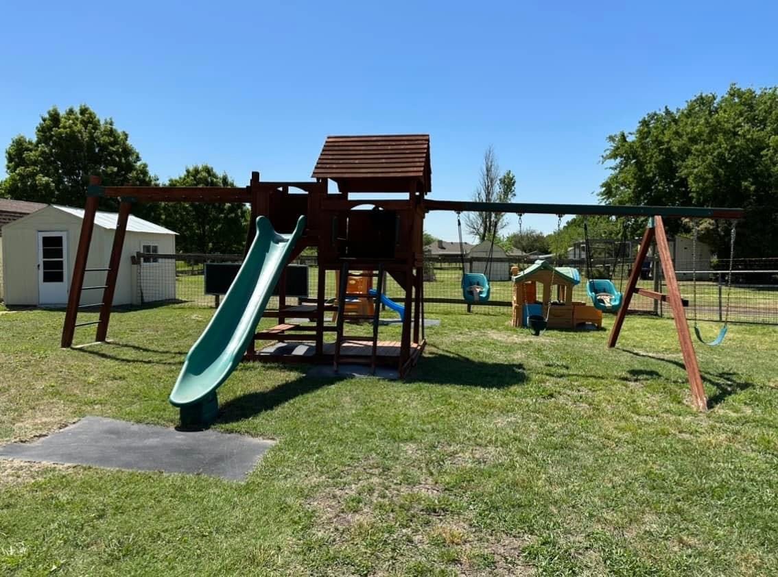 Playground with a slide, swings, and a small playhouse