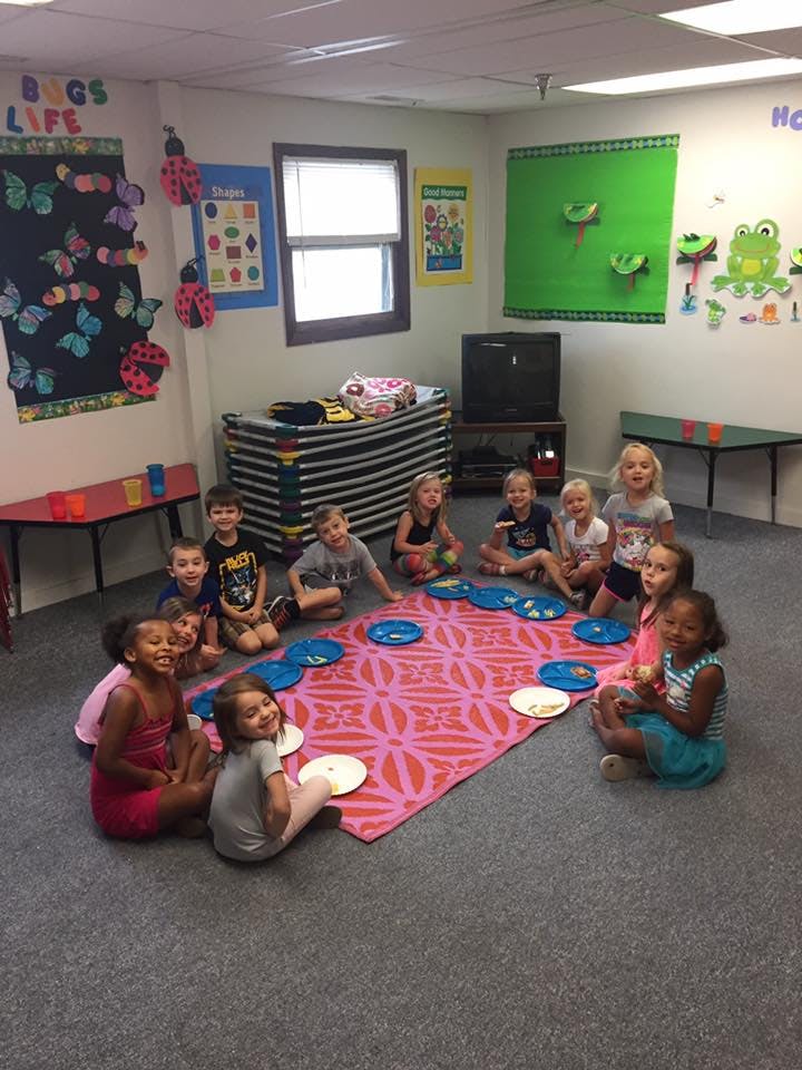 Group of children sitting on a rug in a classroom
