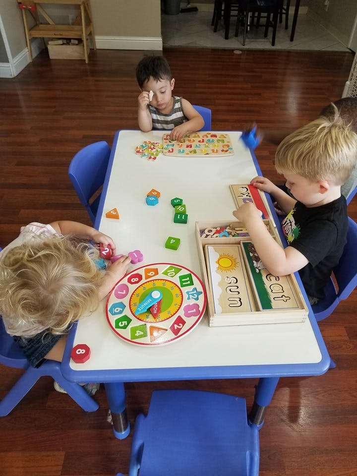 Three children playing with educational toys at a table