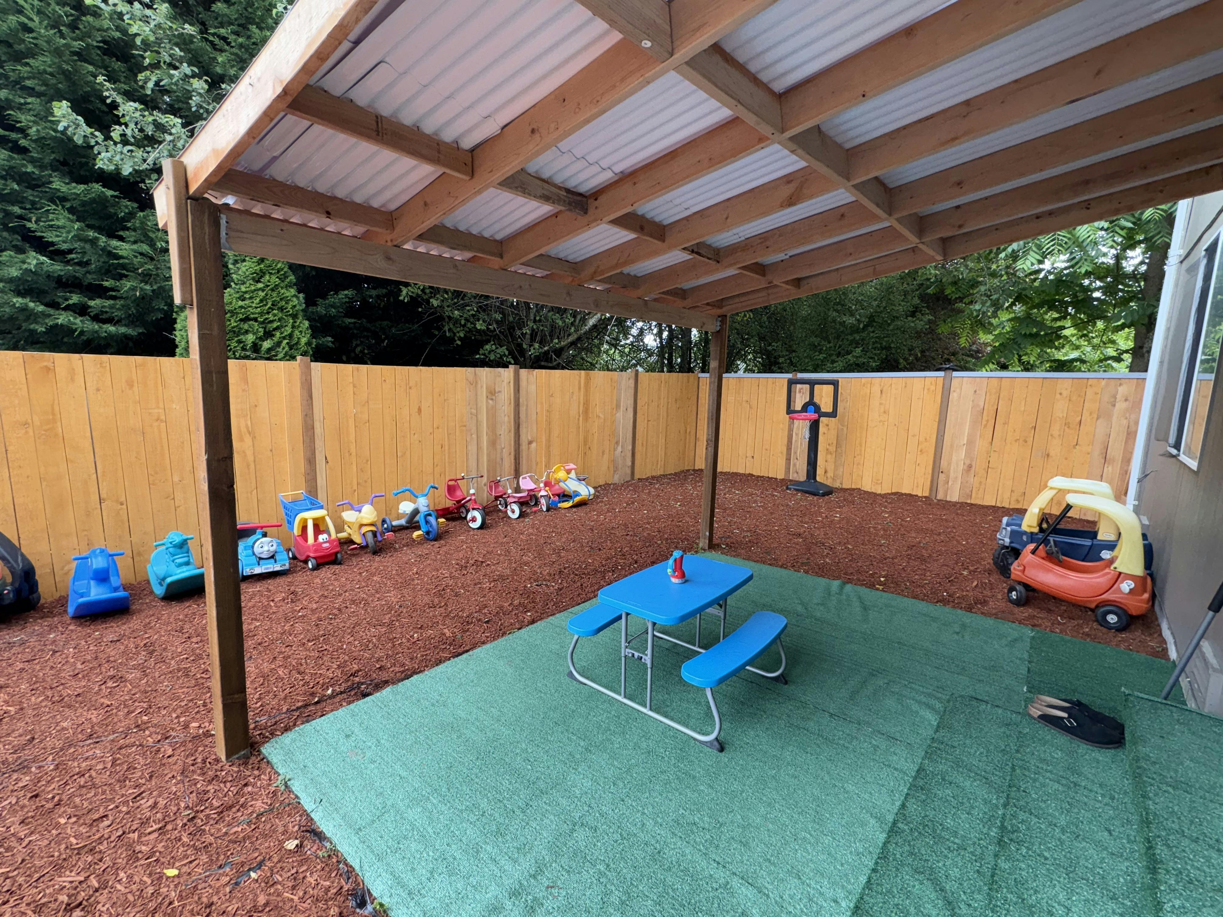 Outdoor play area with a blue picnic table and various ride-on toys