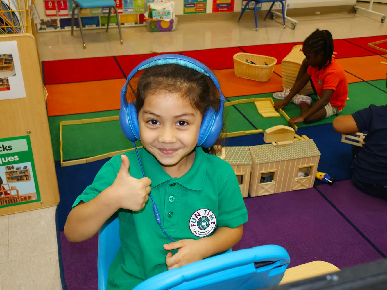 Child wearing headphones giving a thumbs up in a classroom