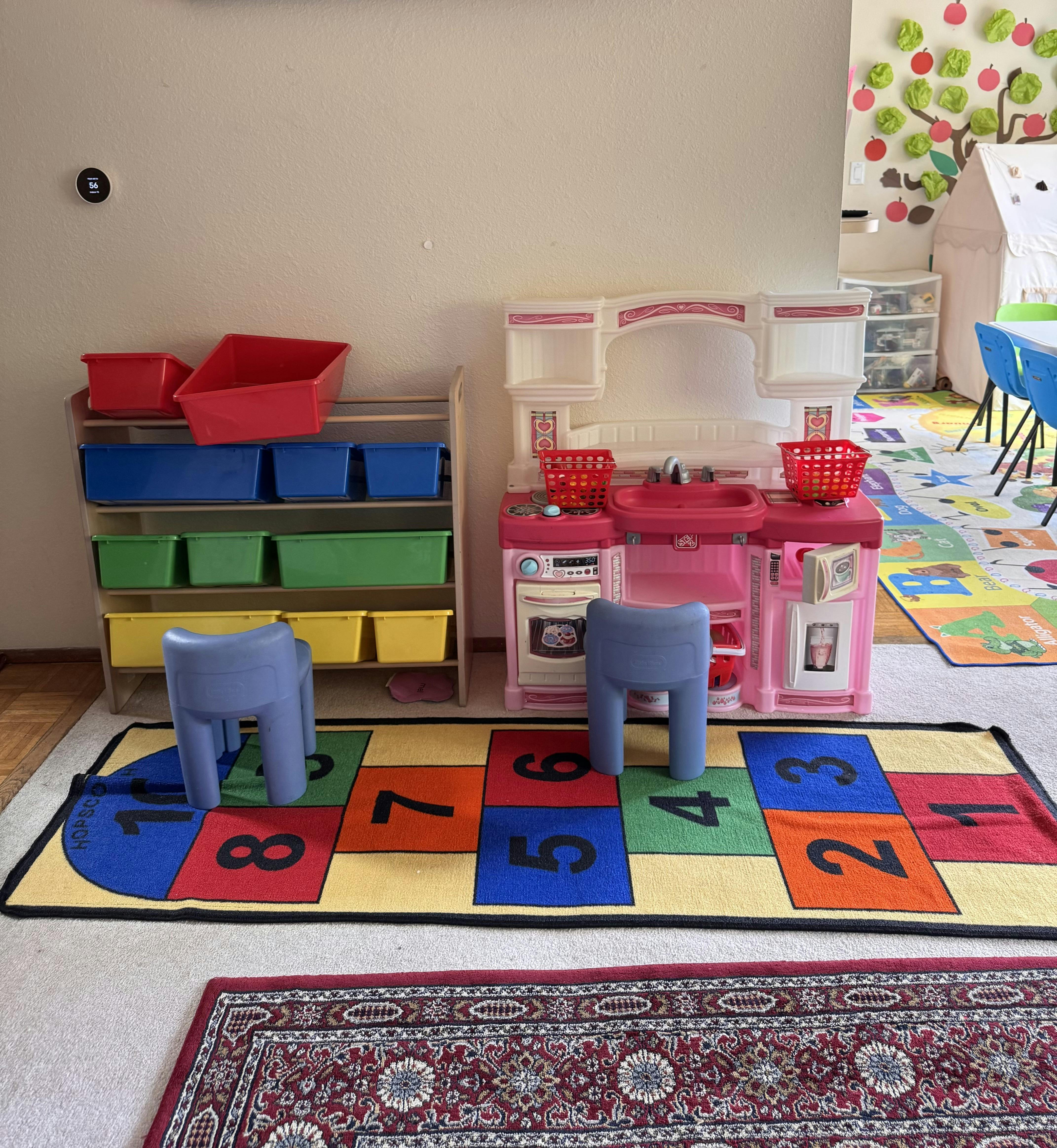 Playroom with toy kitchen, storage shelves, and number rug