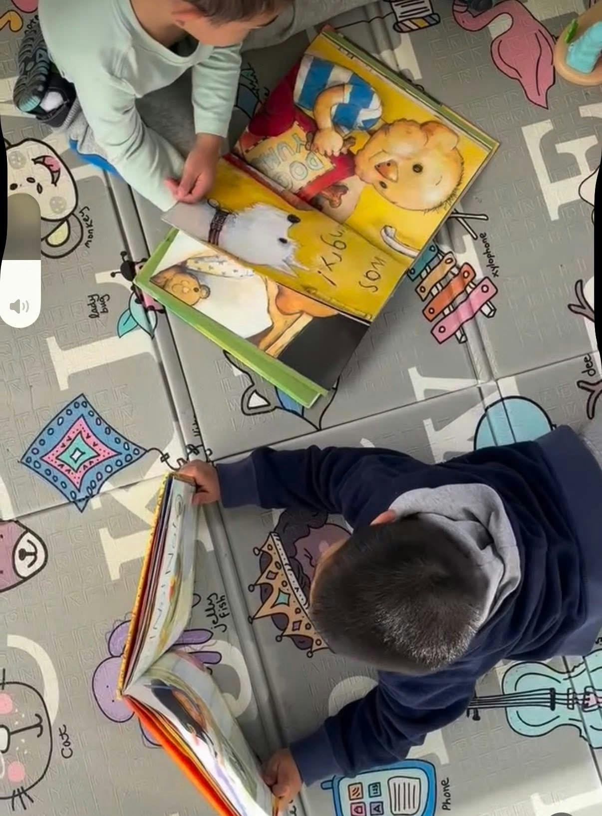 Two children on a mat looking at books