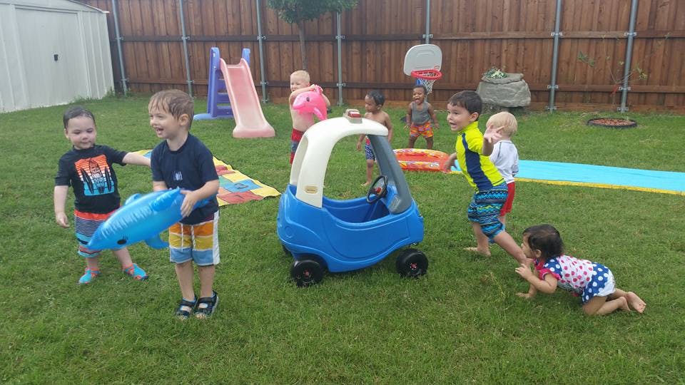 Children playing in a grassy yard with toys