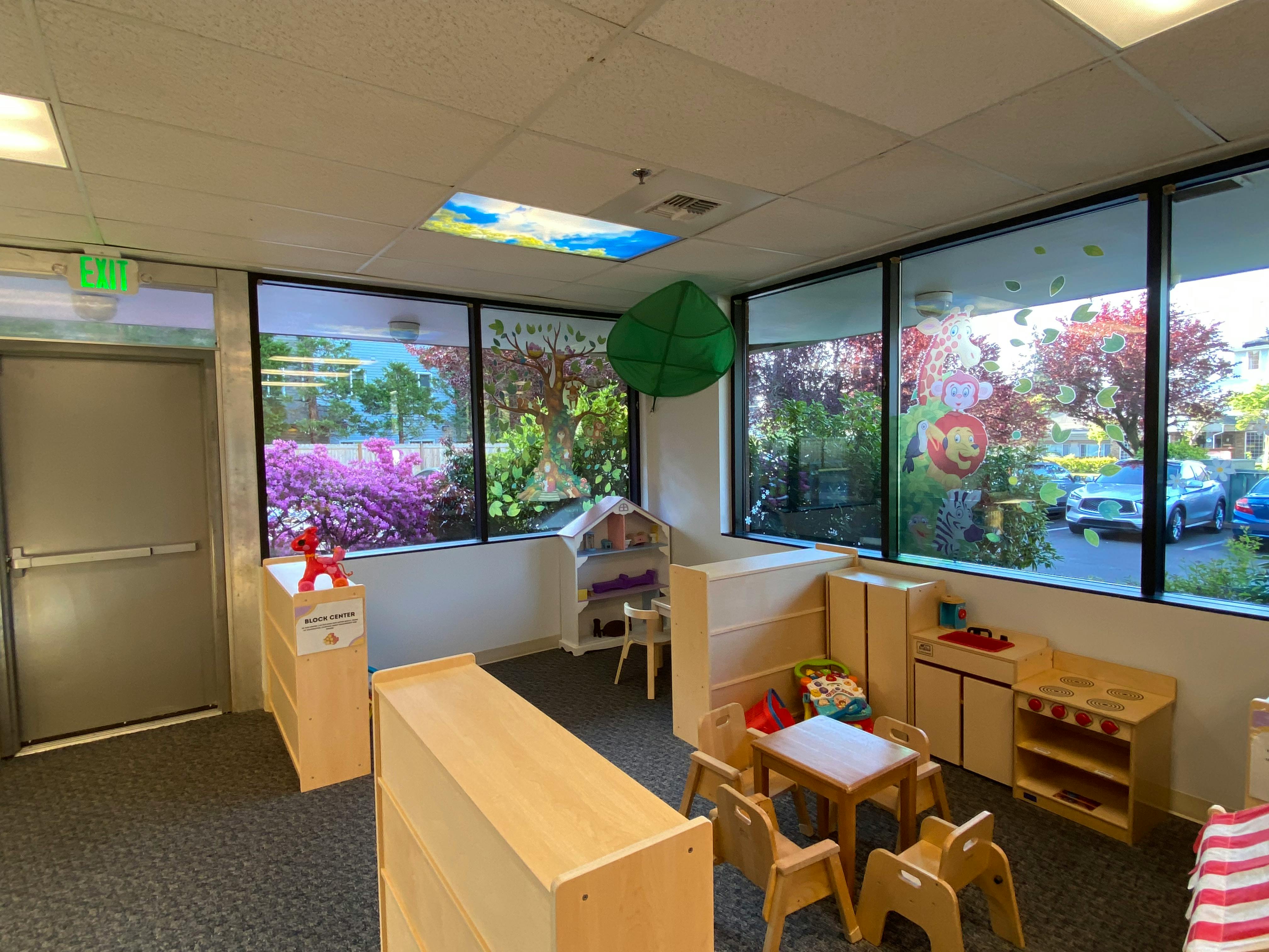 Playroom with children's furniture, large windows, and a green leaf-shaped pillow