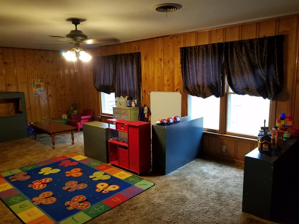 Playroom with colorful rug, small table, and toy storage