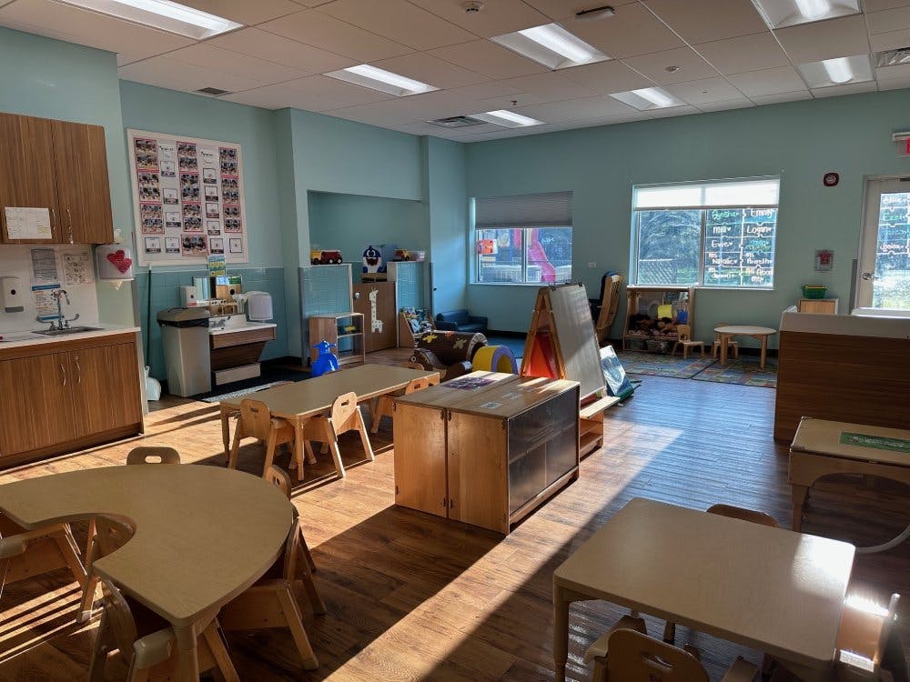 Empty classroom with small tables and chairs, wood floors, and light blue walls