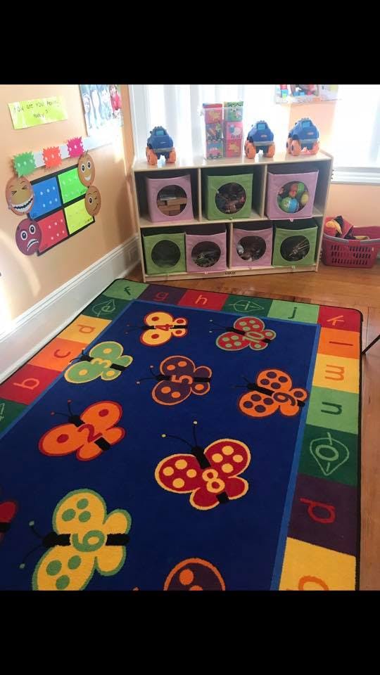 Classroom with a butterfly and alphabet rug and toy storage shelves
