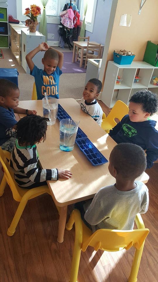 Five children sitting around a table in a classroom