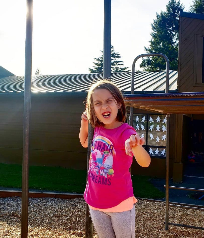 Child on a playground making a face and reaching out