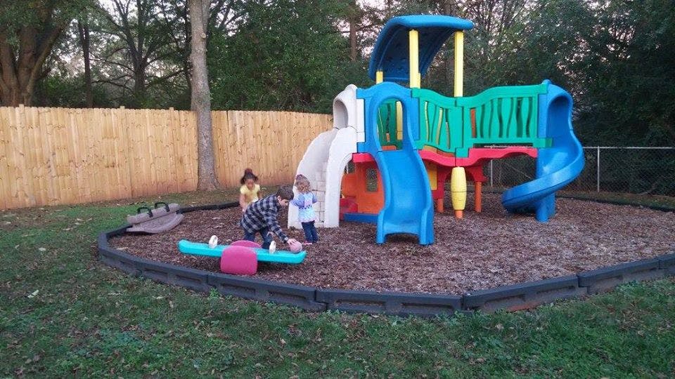 Children playing on a playground with a slide and seesaw