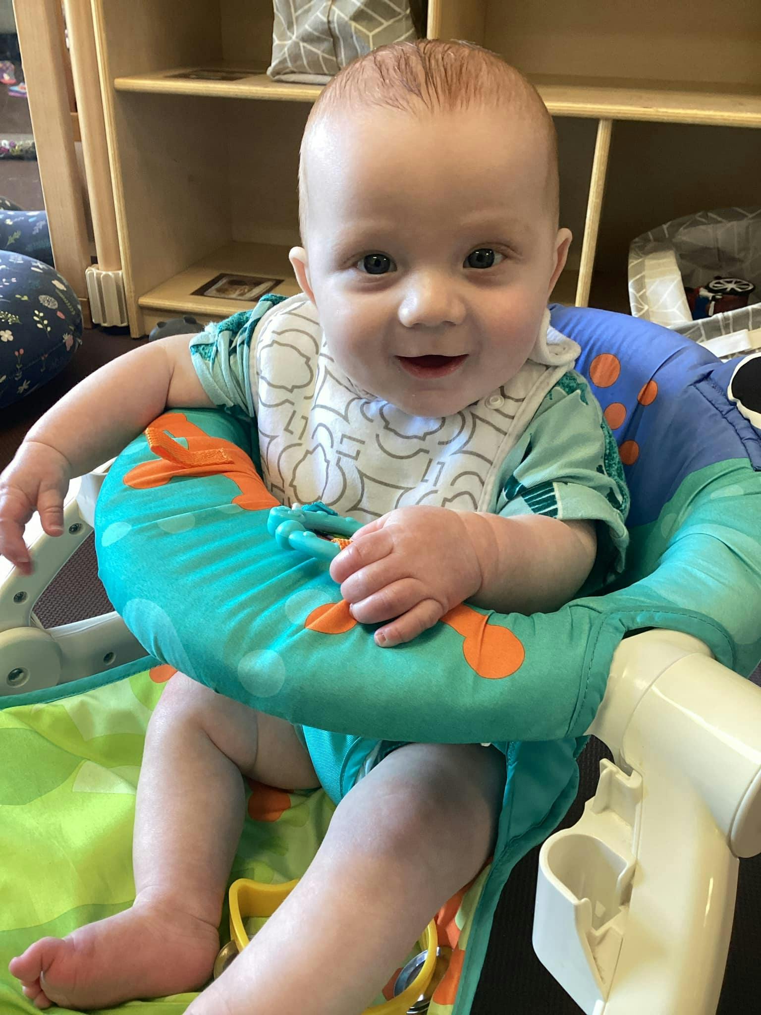 Child in a high chair with a bib