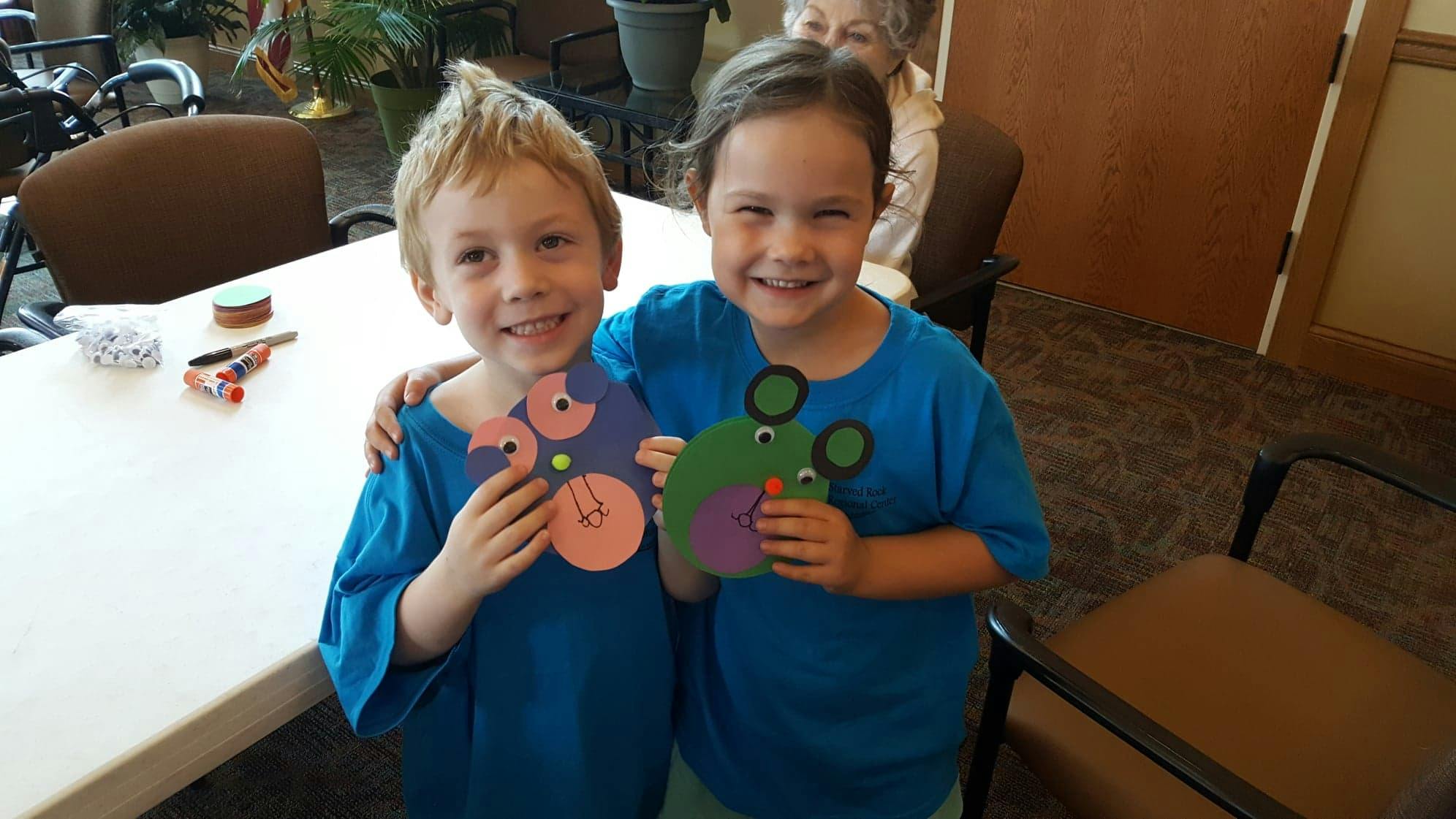 Two children holding up paper crafts
