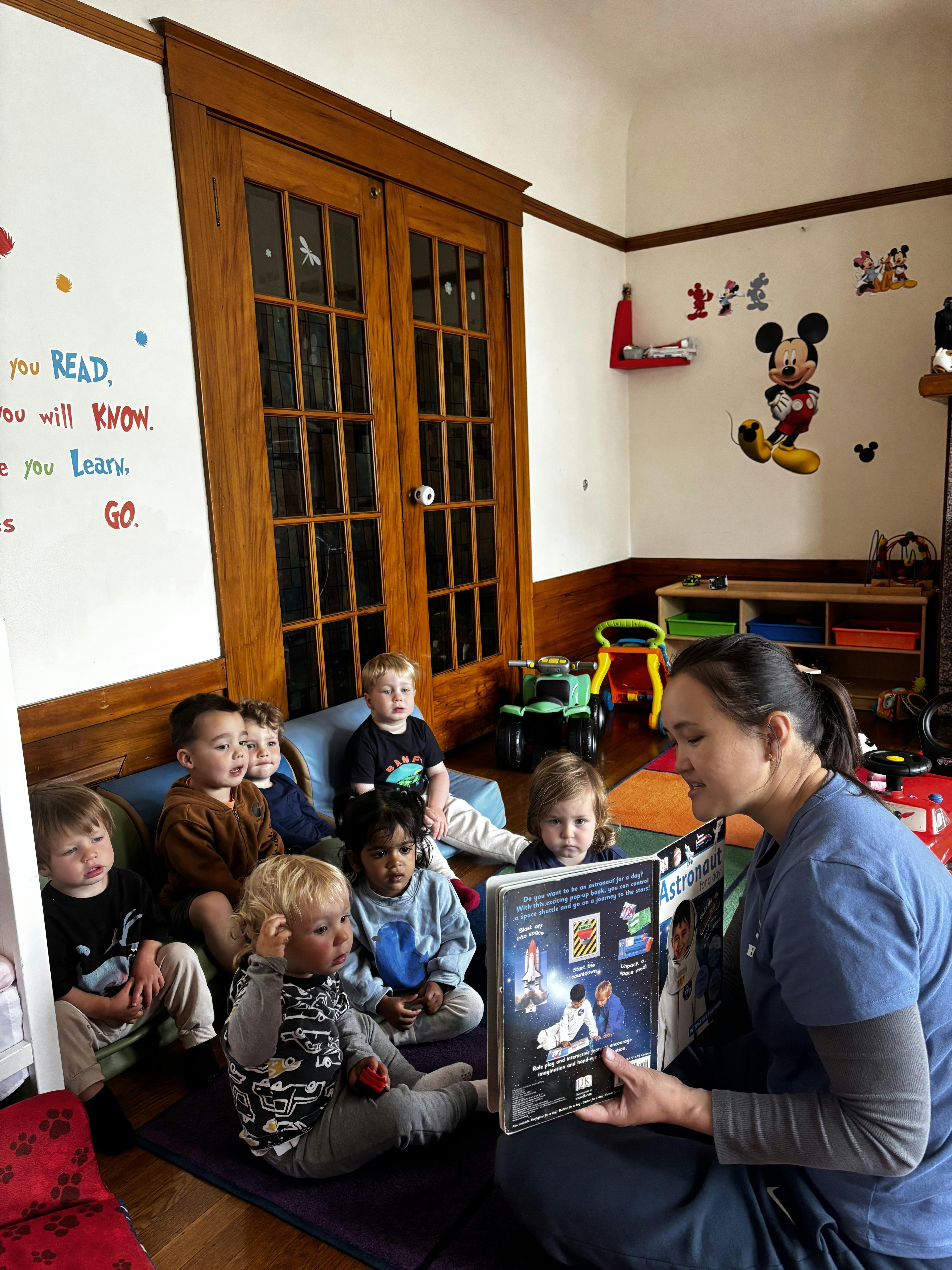 Teacher reading a book to a group of children in a classroom