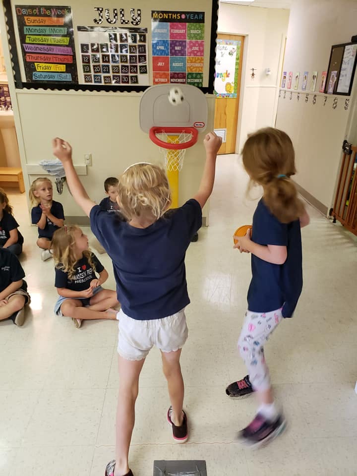 Child playing with a toy basketball hoop in a classroom