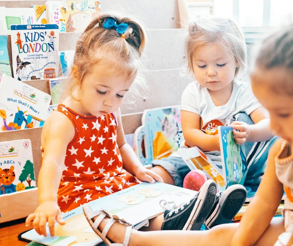 Three children sitting on the floor reading books