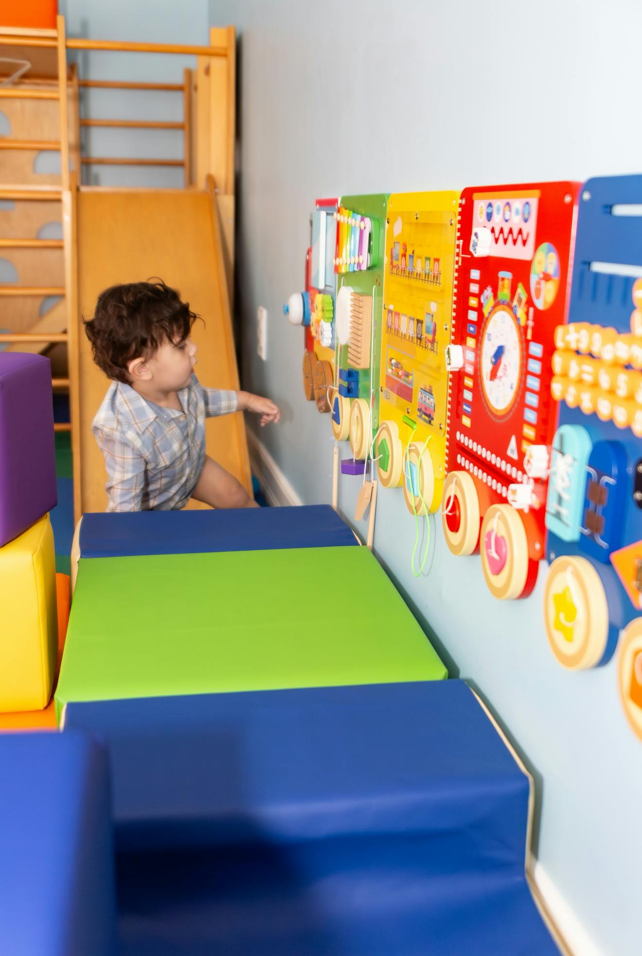 Child playing with a colorful activity board in a play area