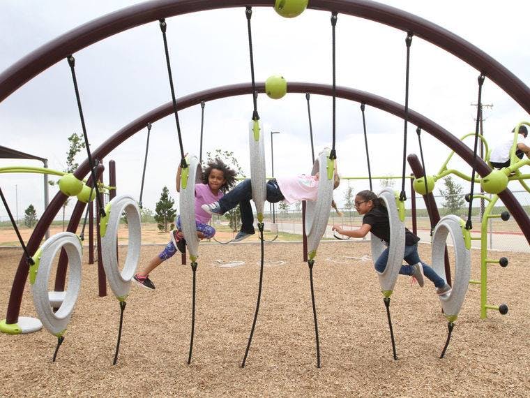 Three children playing on a modern playground structure