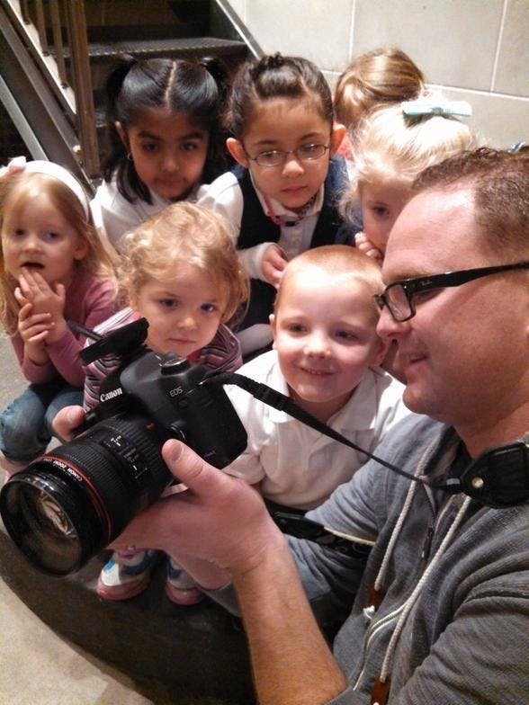 Person holding a camera surrounded by multiple children
