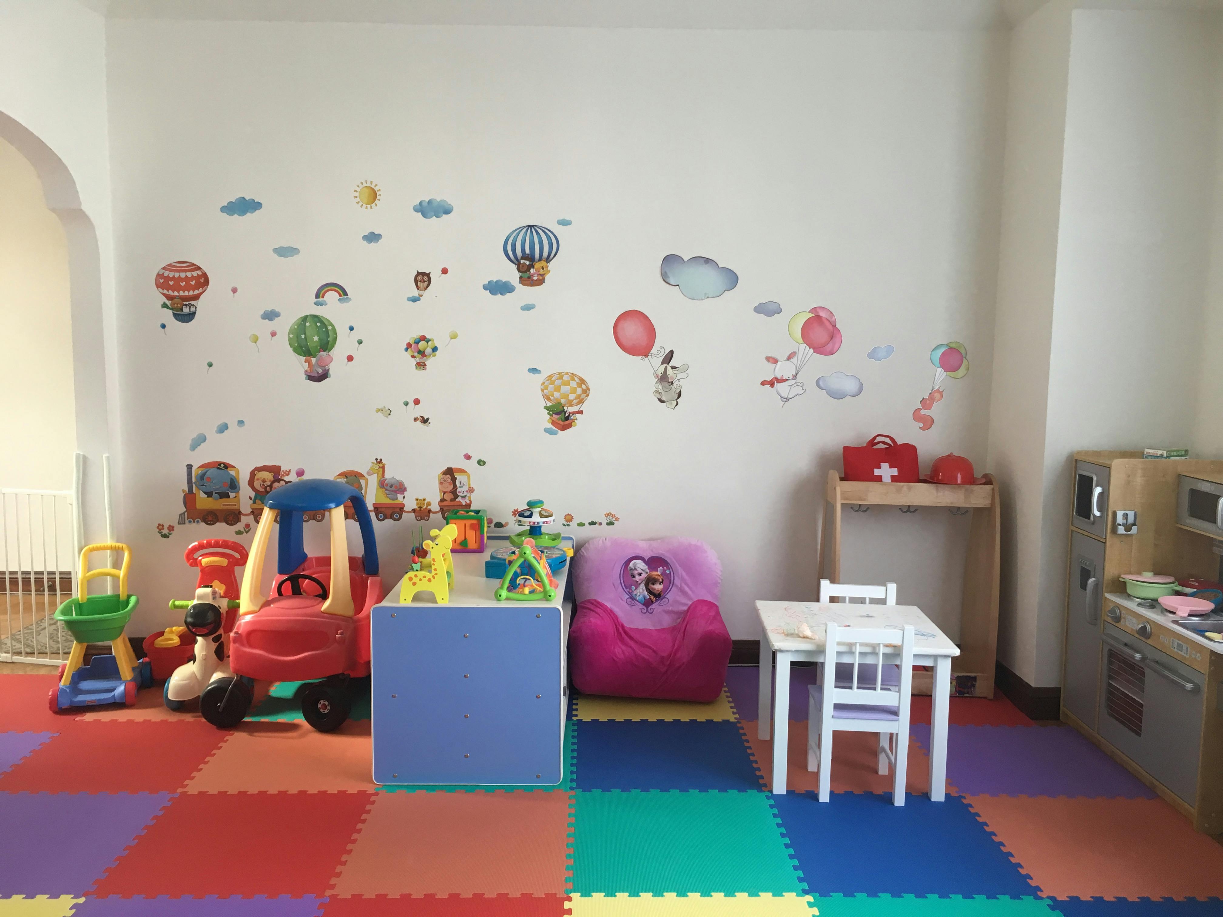 Playroom with colorful floor mats, toys, and wall decals