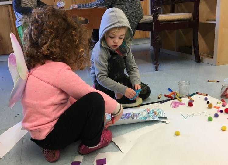 Two children sitting on the floor and crafting