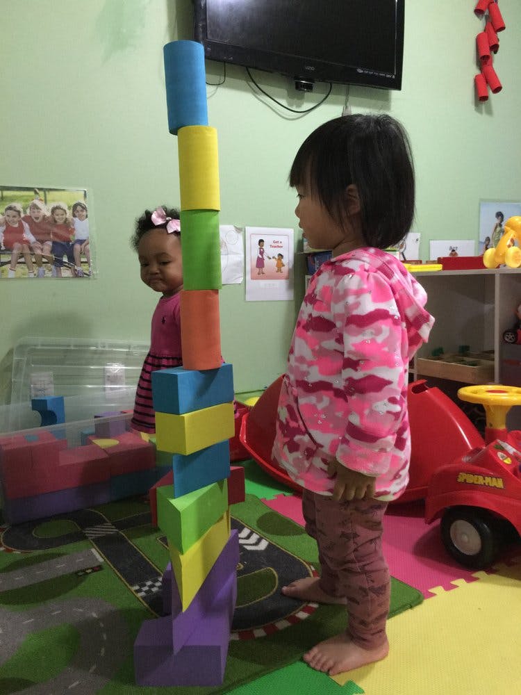 Child standing next to a tall stack of colorful blocks