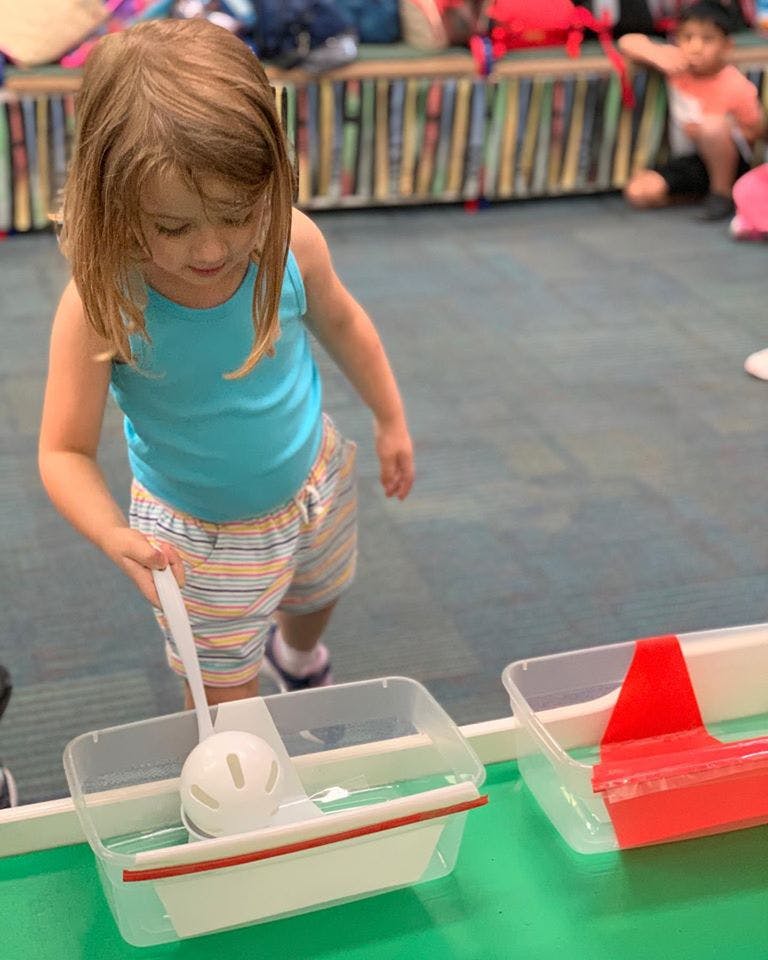 Child holding a ladle over a clear container