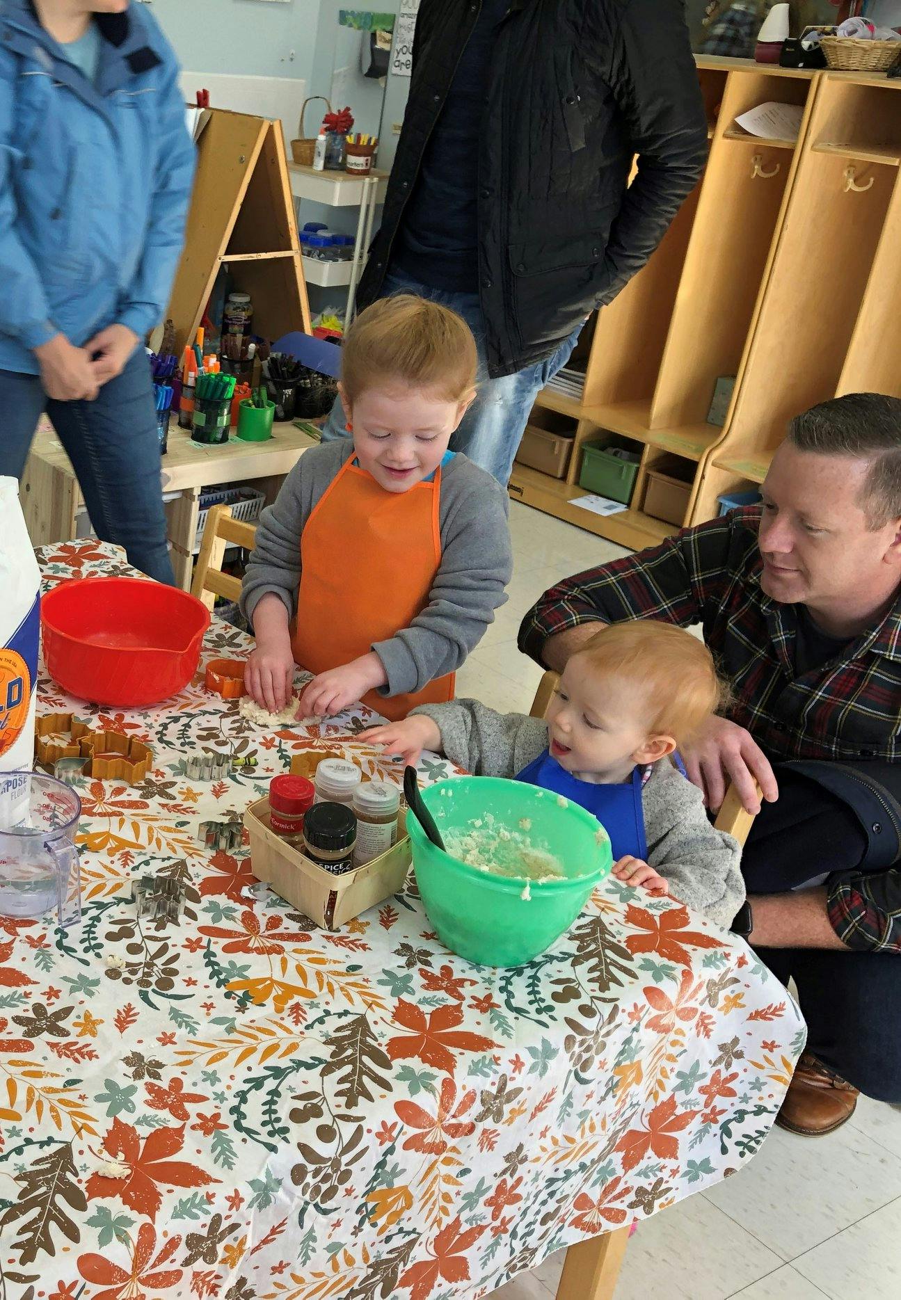 Two children and an adult at a table with bowls and spices