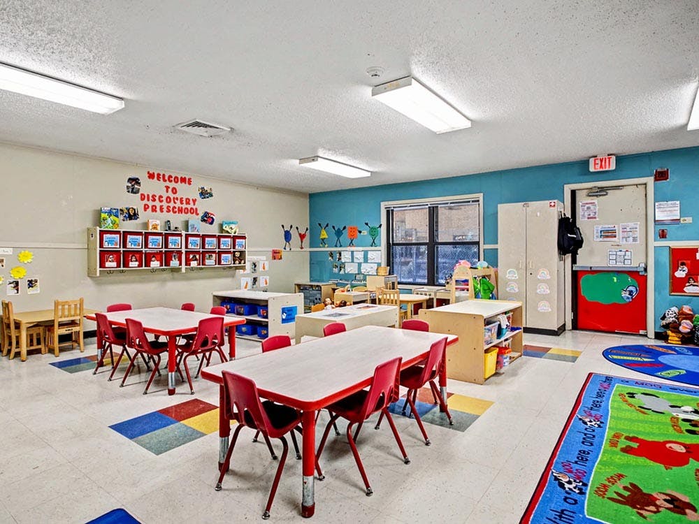 Empty preschool classroom with small tables and chairs