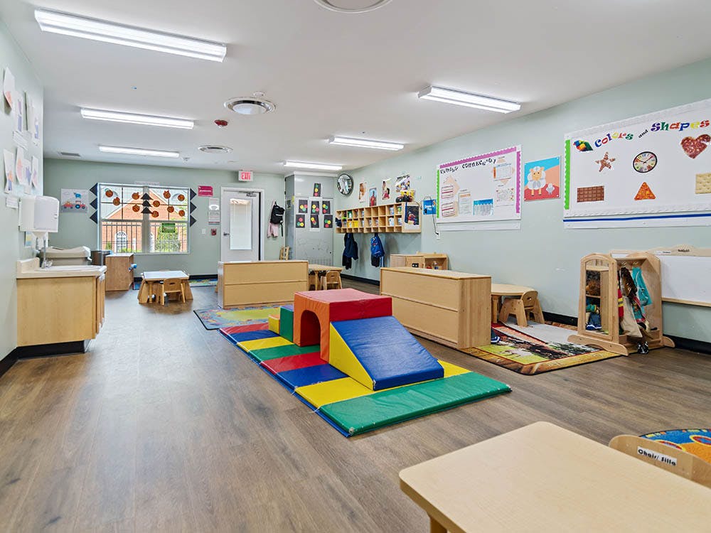 Classroom with small tables, chairs, and colorful soft play equipment