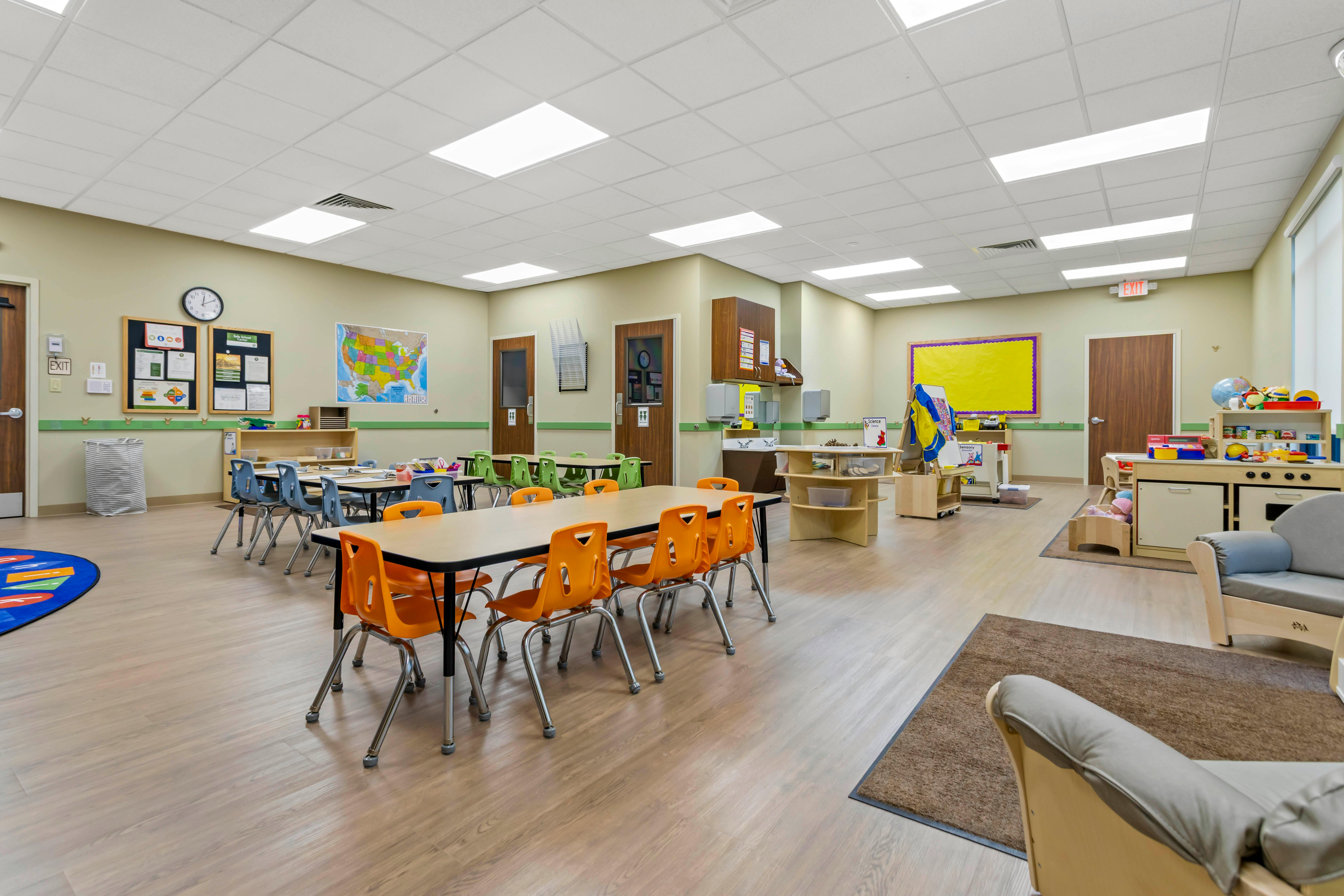 Classroom with multiple tables and chairs, and a play kitchen set