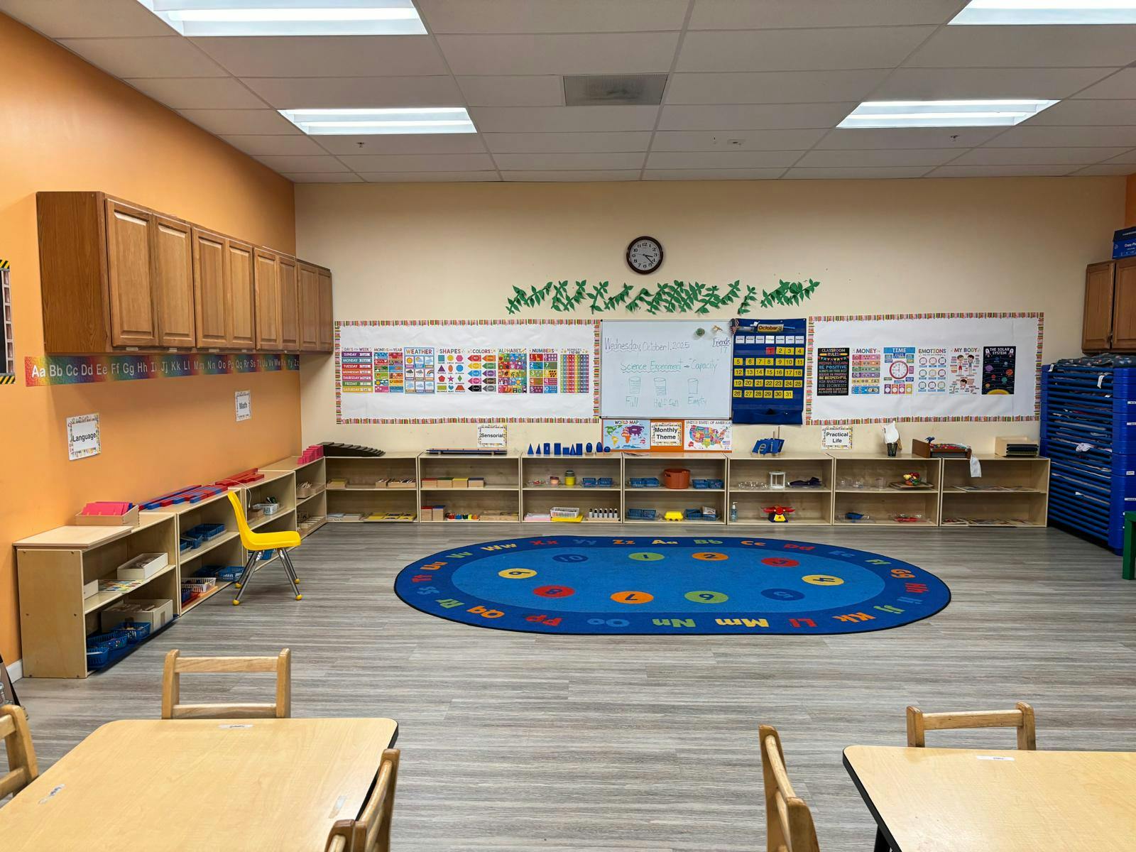 Classroom with child-sized furniture, educational posters, and a blue rug