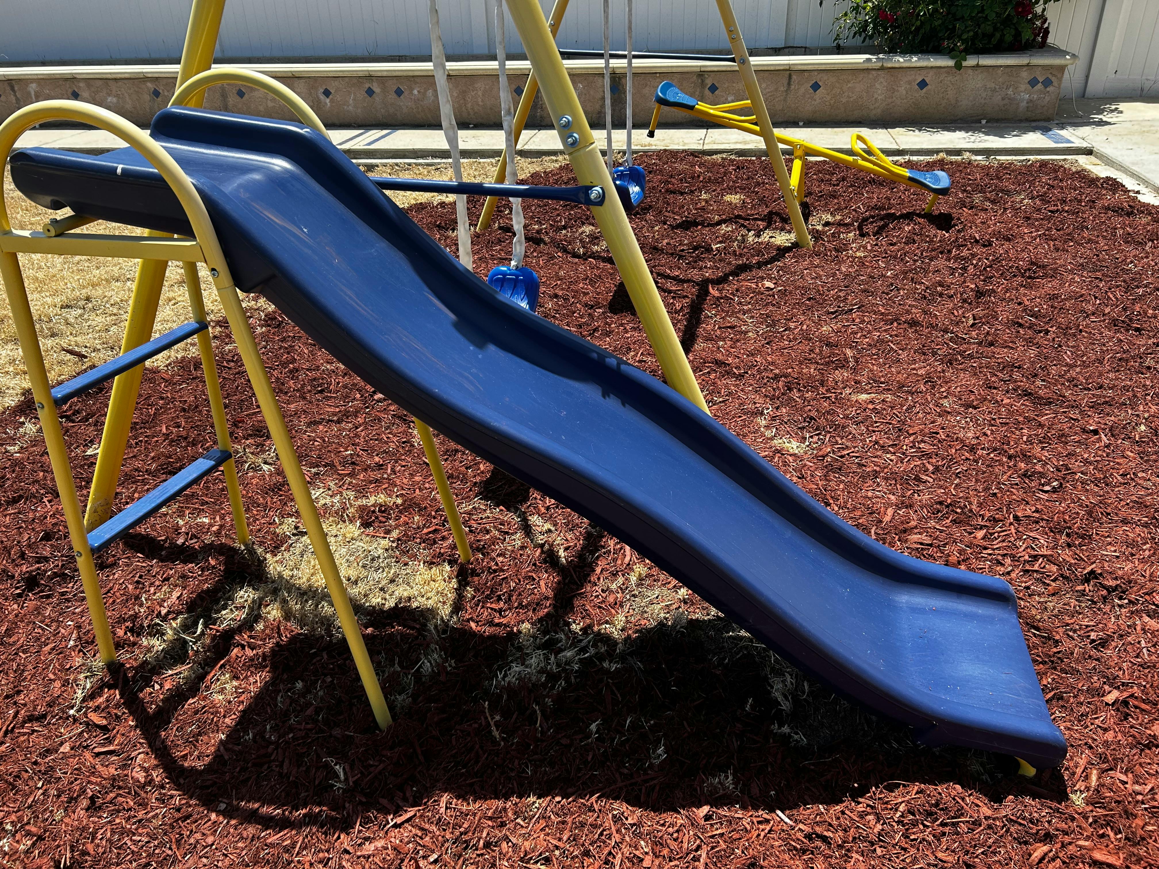 Blue slide on a playground with wood chips