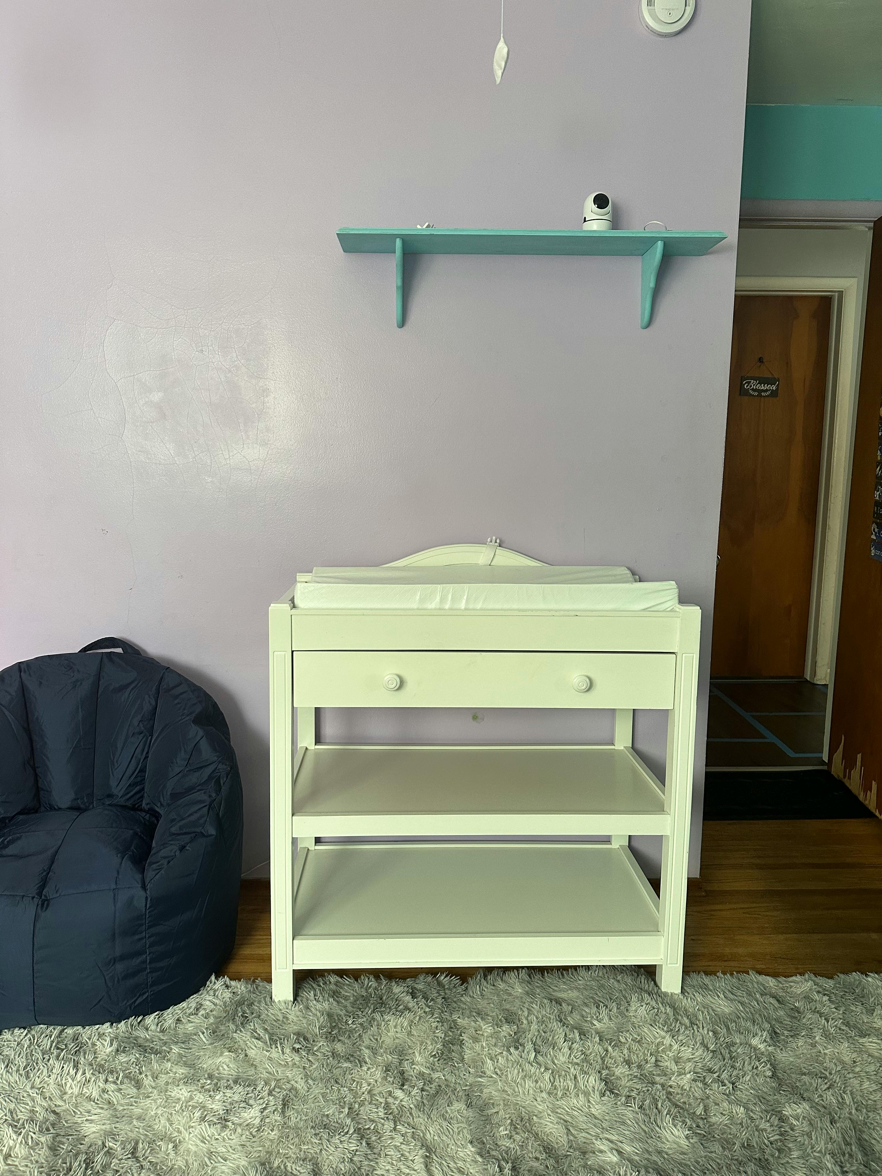 White changing table with shelves and a dark bean bag chair
