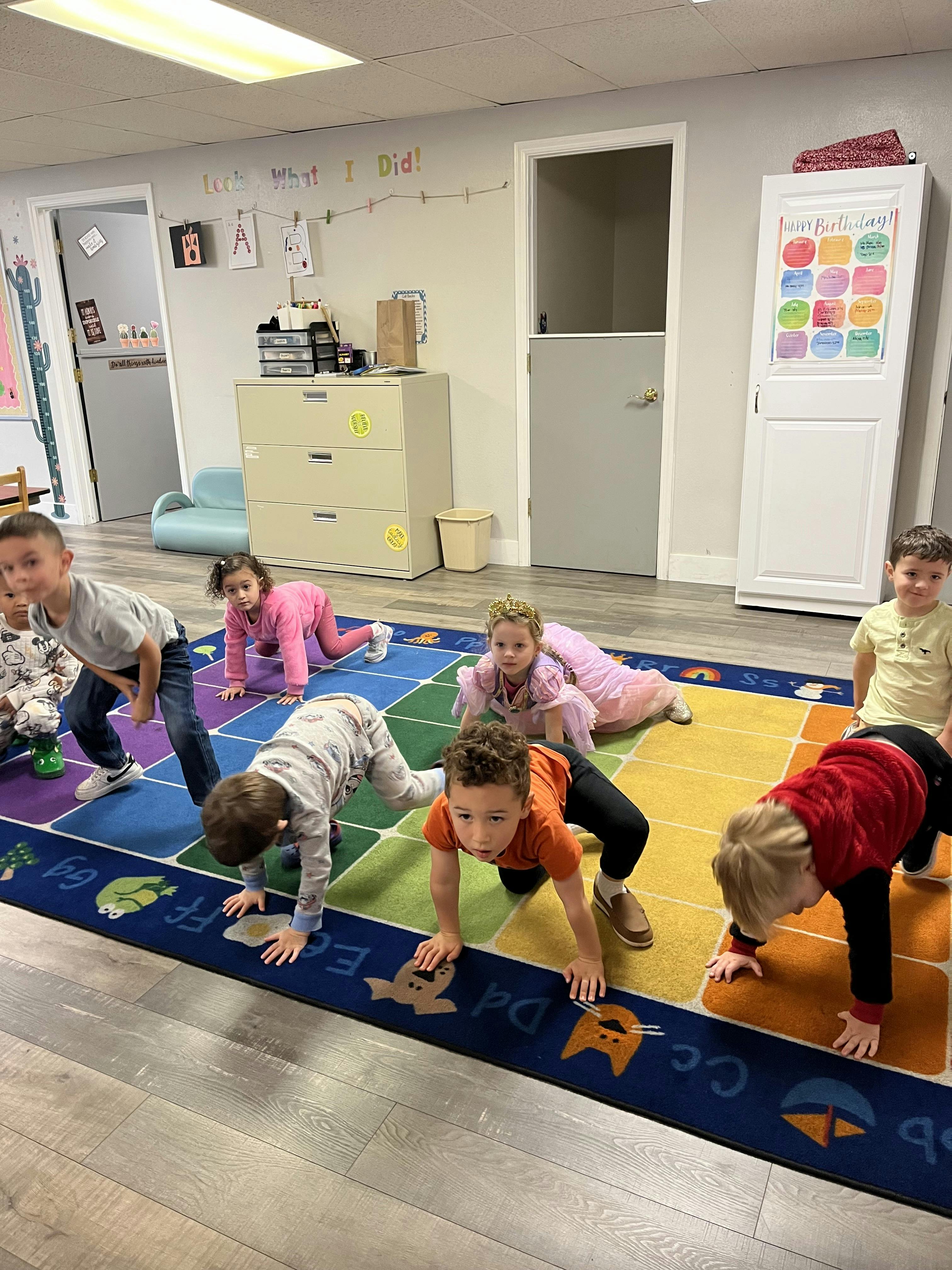 Several children playing on an alphabet rug in a classroom