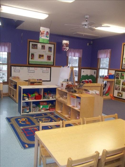 Classroom with purple walls, small tables, and shelves of toys
