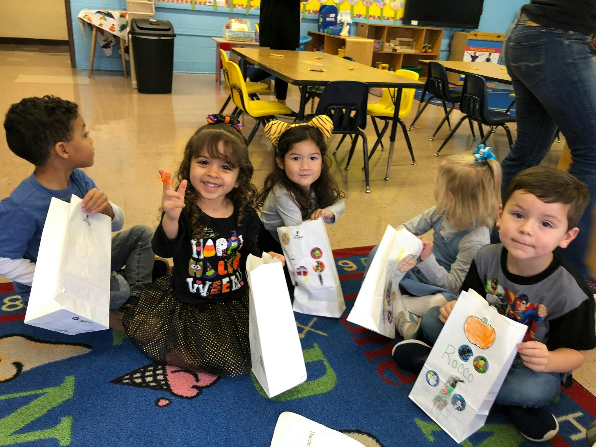 Children sitting on a rug with white bags